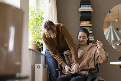 Nurse assisting woman with paraplegia sitting on wheelchair at home