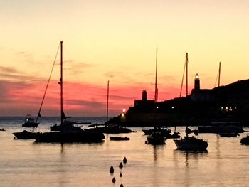 Silhouette sailboats in sea against sky during sunset