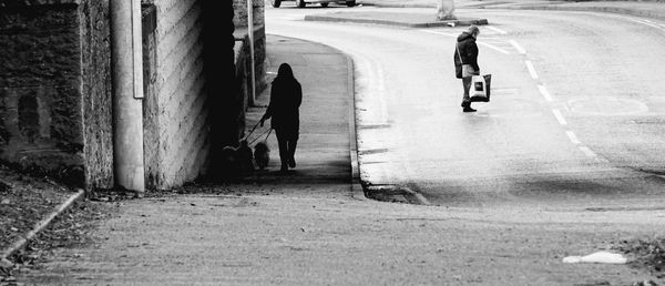 Rear view of people walking on street in city