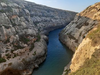 Rock formations by river against sky