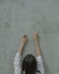 Rear view of young woman wearing rose shape rings by wall