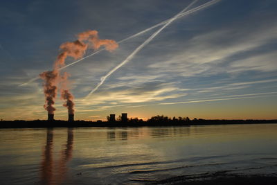 Smoke emitting from factory against sky during sunset