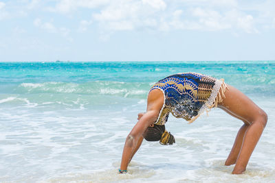 Young adult on beach against sky