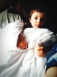 Portrait of cute boy lying on bed at home