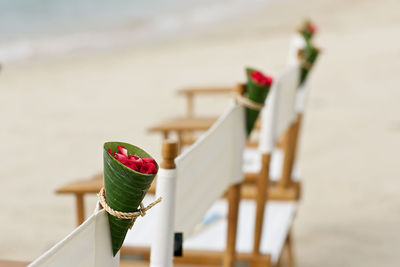 Close-up of rose petals in banana leaf cone on chair at beach