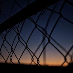 Silhouette fence against sky during sunset