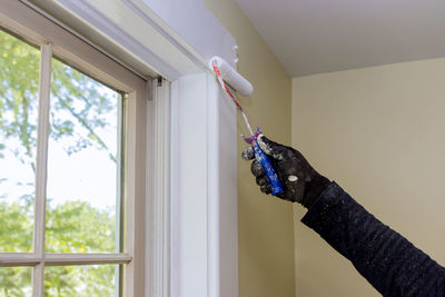 Midsection of man holding glass window at home