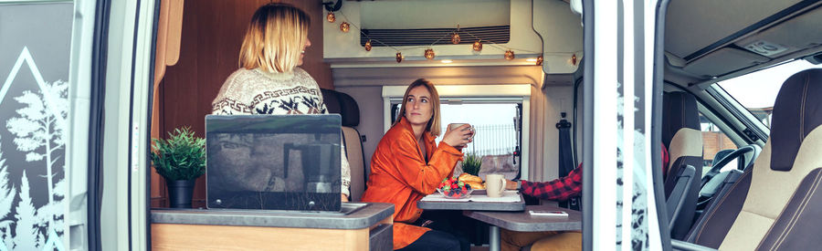 Friends having breakfast in a camper van in the morning