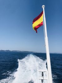 Flag on sea against clear blue sky