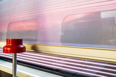 Red lamp on a public train waiting for departure with another train passing outside the window