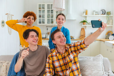 Portrait of happy friends using mobile phone
