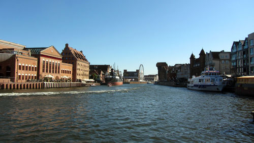 River amidst buildings against clear blue sky