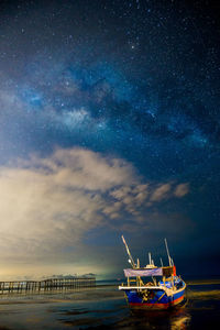 Boat sailing in sea against sky at night