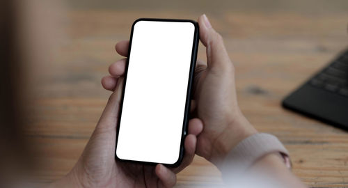 Midsection of person holding smart phone on table