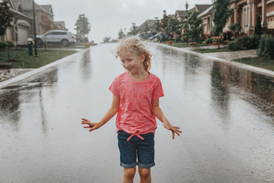 Happy girl standing on wet road during rainy season