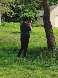 Rear view of woman photographing in field