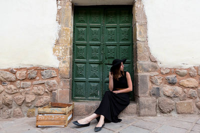 Young woman sitting on doorway of old house
