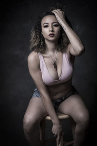 Portrait of a beautiful young woman sitting against black background