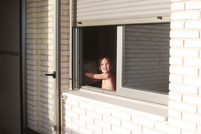 Portrait of little boy looking through window