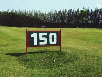 Information sign on field against sky