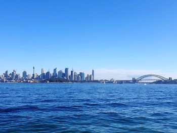 View of buildings by sea against blue sky