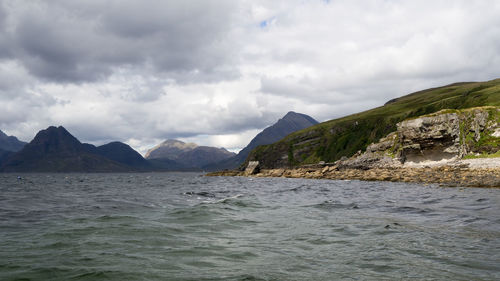 Scenic view of sea and mountains against cloudy sky