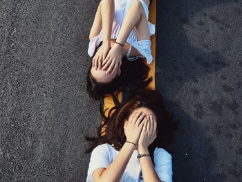 Directly above shot of women covering face while lying on road