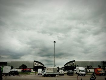 Cars on road in city against storm clouds