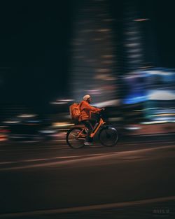 Blurred motion of man riding motorcycle on road at night