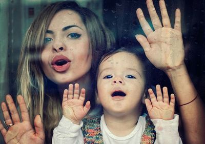 Close-up portrait of woman and girl behind window