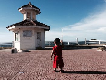 Rear view of boy standing by sea against sky