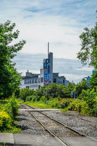 Railroad tracks amidst trees and buildings against sky