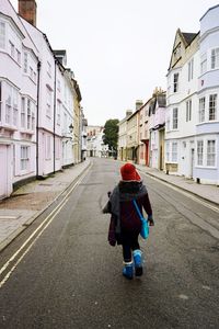 Rear view of woman walking on street amidst buildings in city