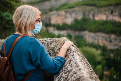 Side view of woman wearing sunglasses on rock