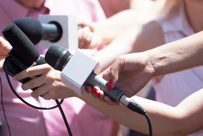 Midsection of reporters holding microphones