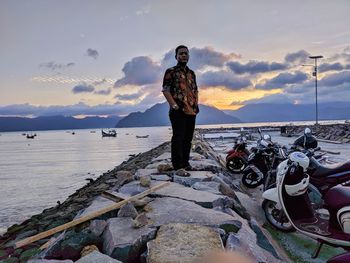 Full length of man standing on rock formation by sea against sky