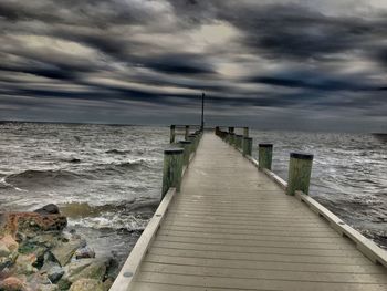 Pier on sea against cloudy sky