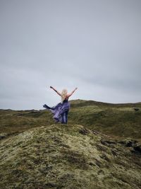 Rear view of woman in lava field against clear sky