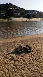 Close-up of shoes on sand at beach against sky