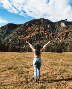 Young woman, rear view, back view, standing in valley, autumn, fall, arms outstretched.