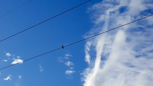 Low angle view of power lines against cloudy sky