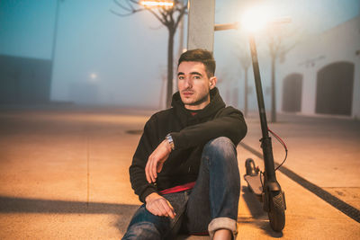 Man sitting next to his electric scooter. he is looking at camera