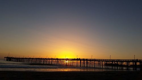 Silhouette pier over sea against sky at sunset