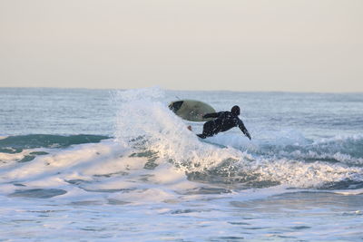 Man surfing in sea against sky