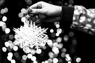 Cropped hand of woman holding illuminated string lights