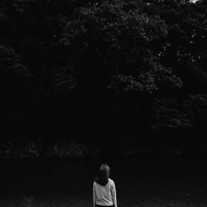 Rear view of woman standing against tree