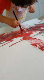 Close-up of hand holding paper painting on table