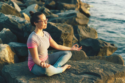 Woman sitting on rock by sea