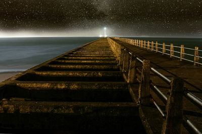 Staircase by sea against sky at night