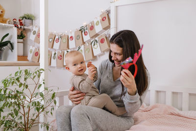 Mother with infant child having fun christmas advent calendar tasks and gifts. baby boy excited